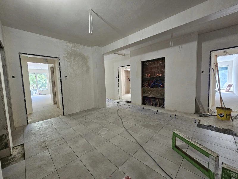 zdjęcie przedstawia pomieszczenie, w którym kładzione są szare prostokątne kafle na podłodze